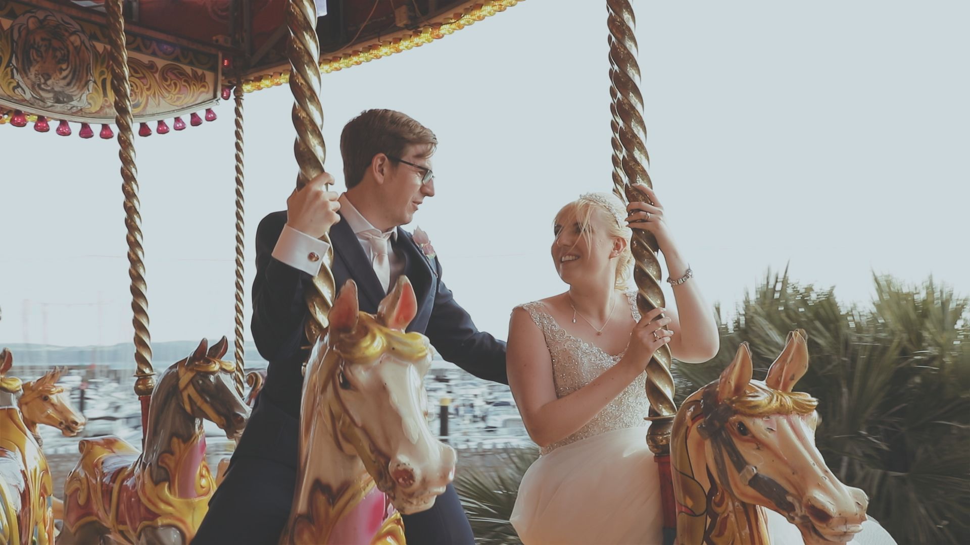 Wedding couple riding a colourful vintage carousel, sharing a joyful portrait moment