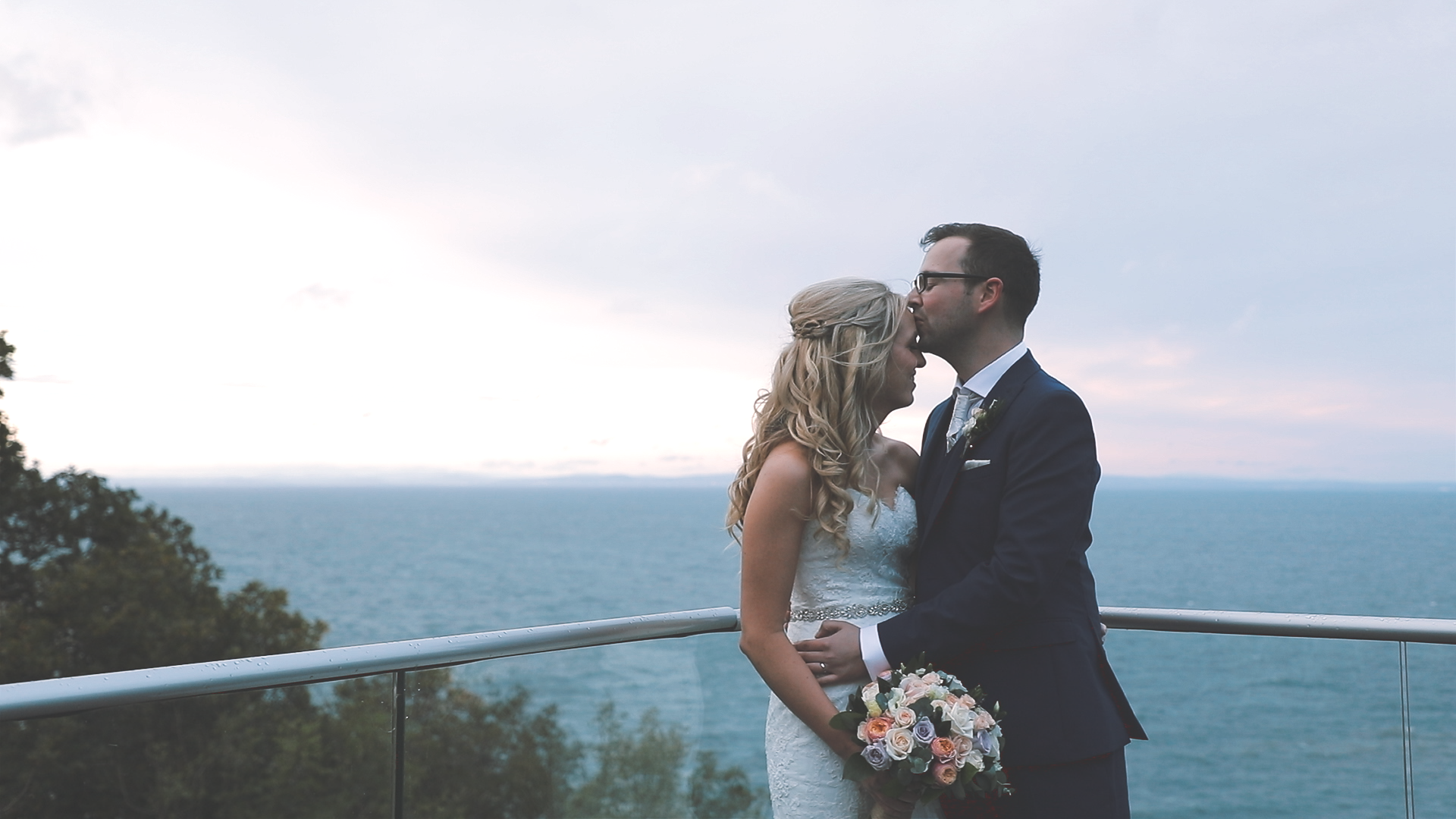 Sunset wedding portrait at Sandy Cove in Devon with bride and groom on a balcony overlooking the ocean