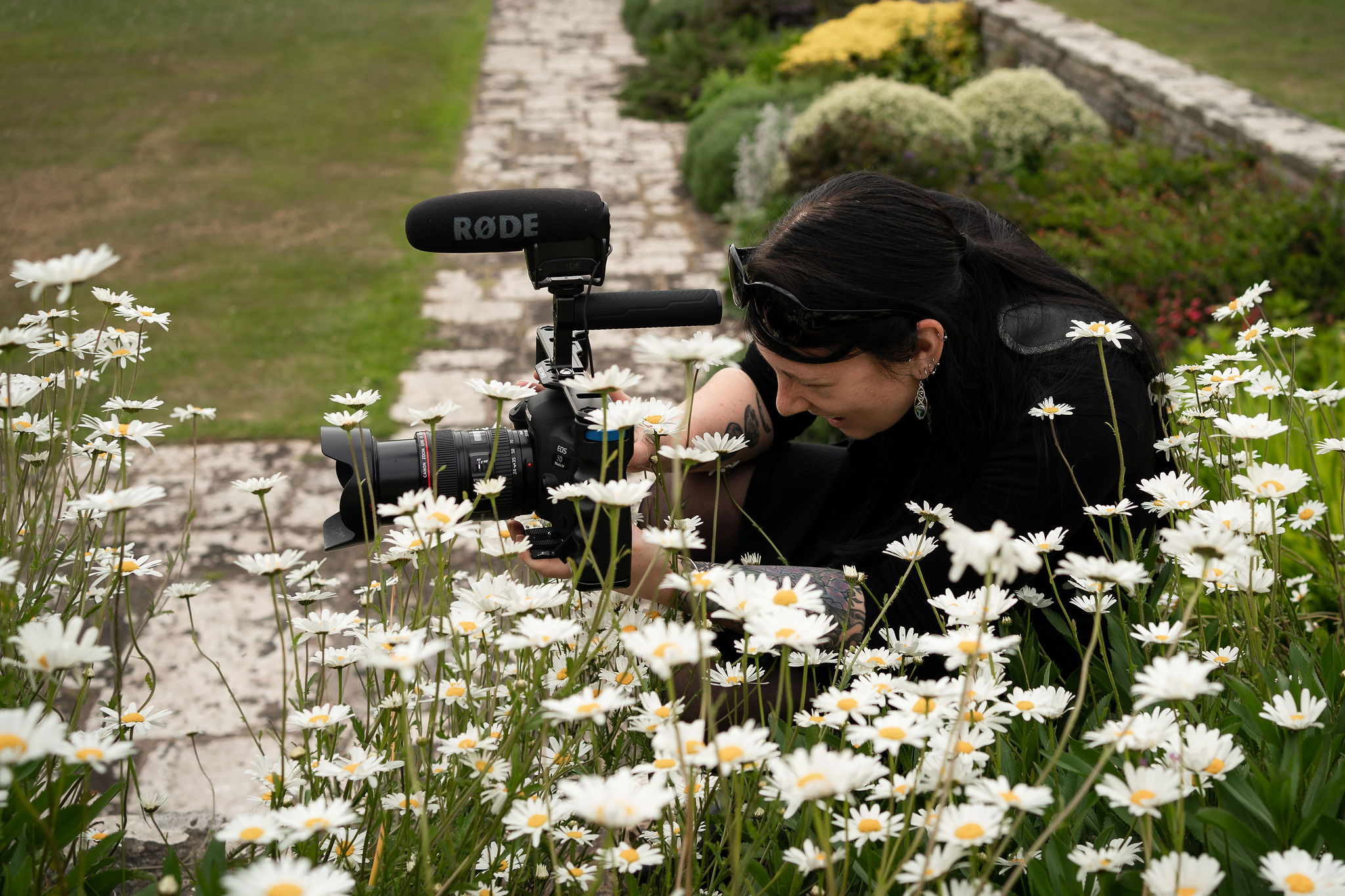Behind-the-scenes female wedding videographer filming a wedding, capturing candid moments with a professional camera and microphone during a wedding at Rockbeare Manor