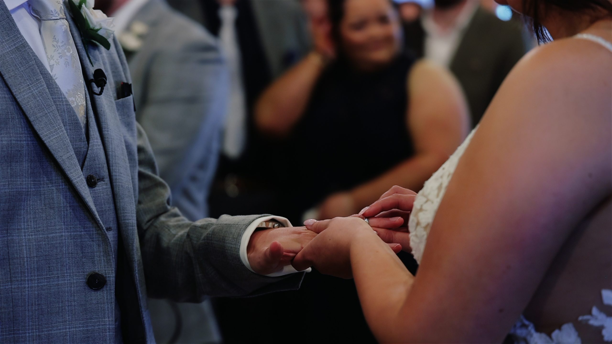 A close up of a bride placing a ring on the grooms finger