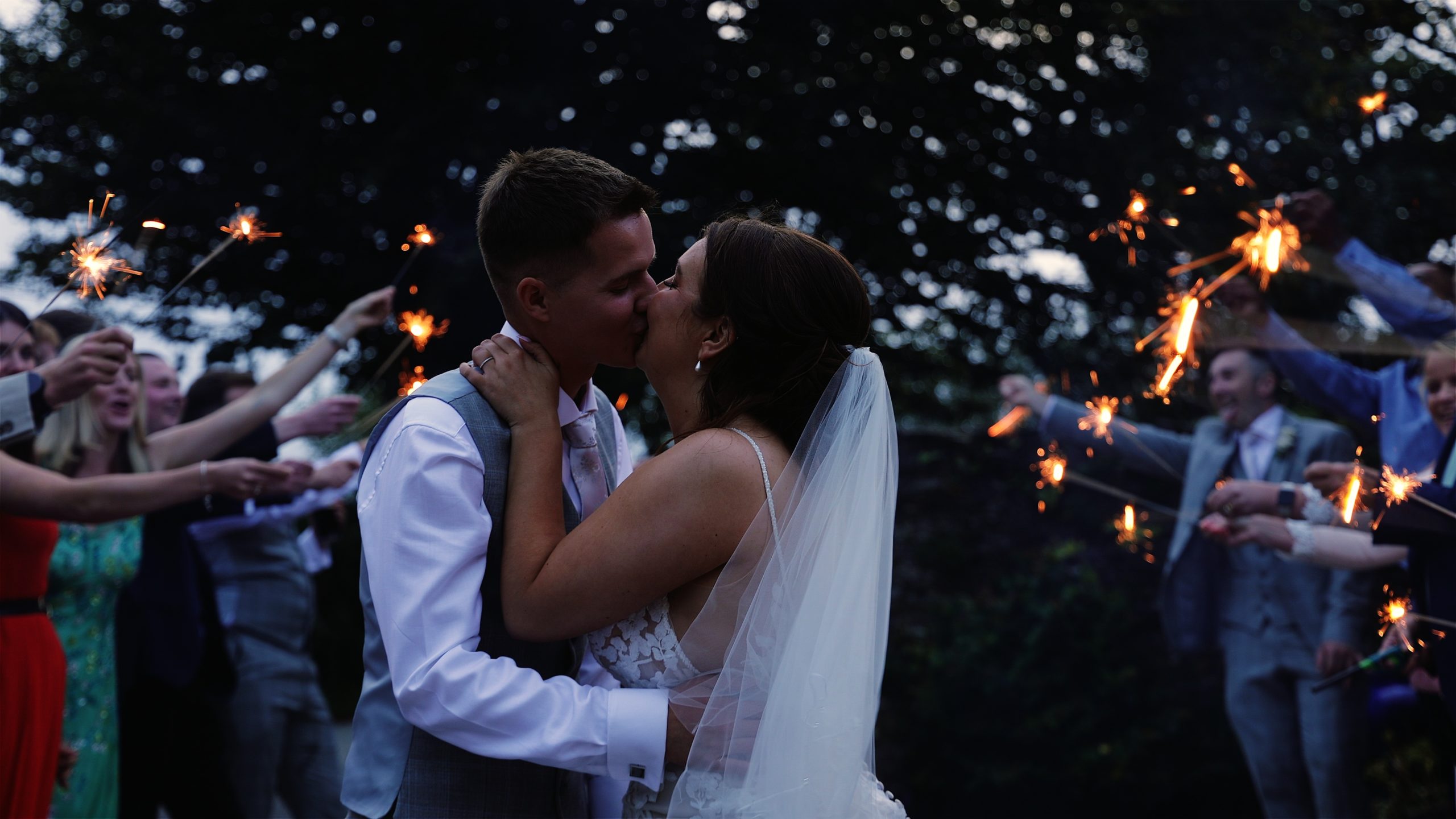 A bride and groom sharing a kiss during a tunnel of sparklers