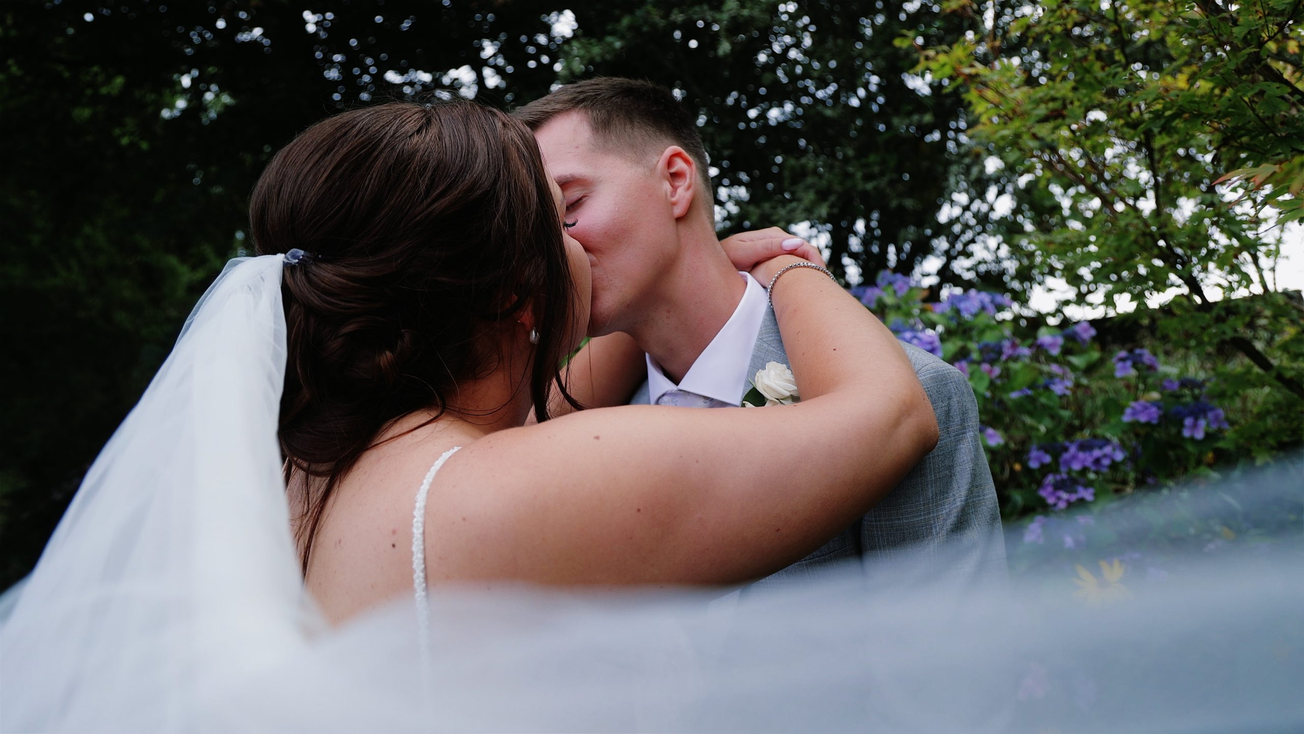 A wedding couple sharing a kiss with the brides veil flowing around them