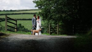 A wedding planning couple with their dog standing in a lane at Trevenna Barn