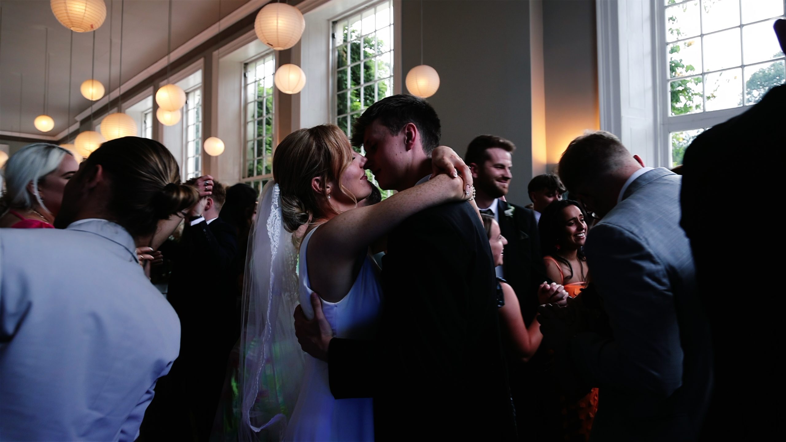 A wedding couple sharing a kiss during their first dance with guests around them