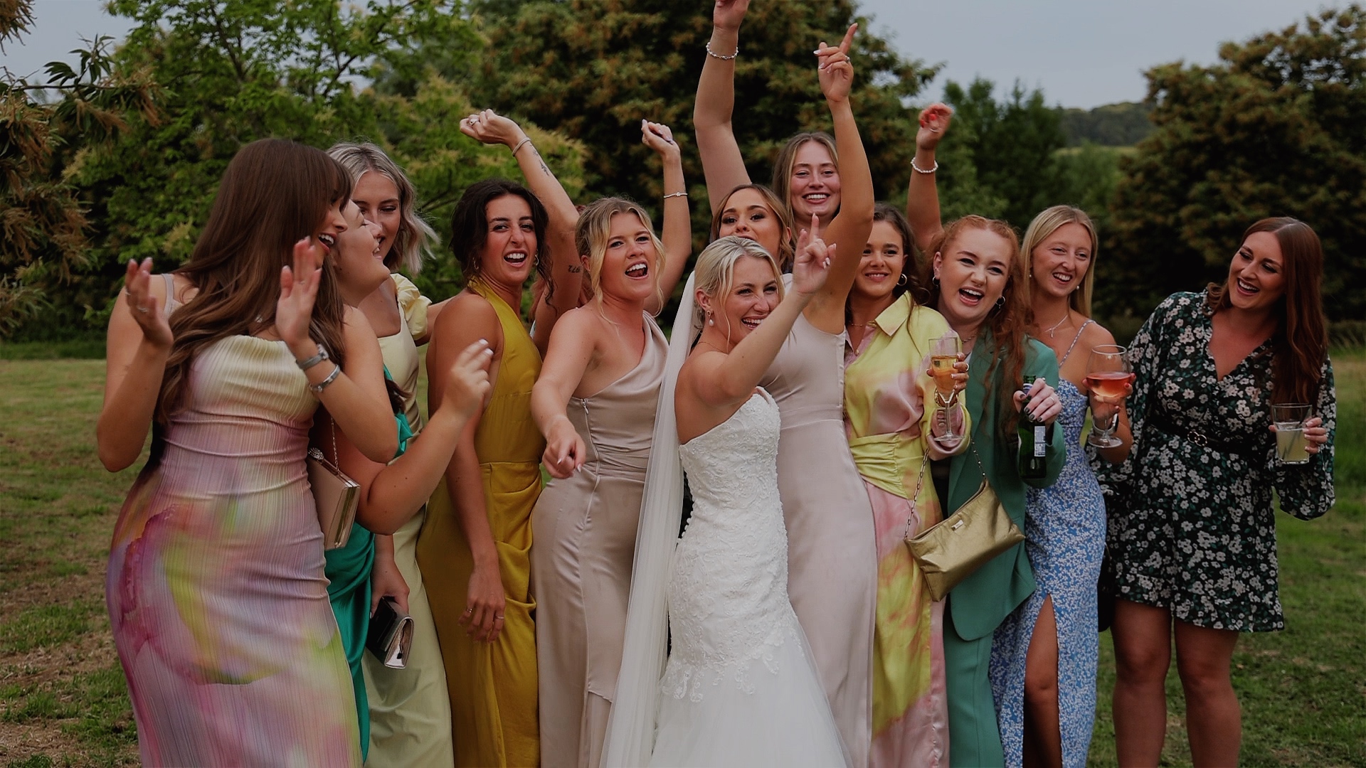 A bride surrounded by her friends singing and dancing