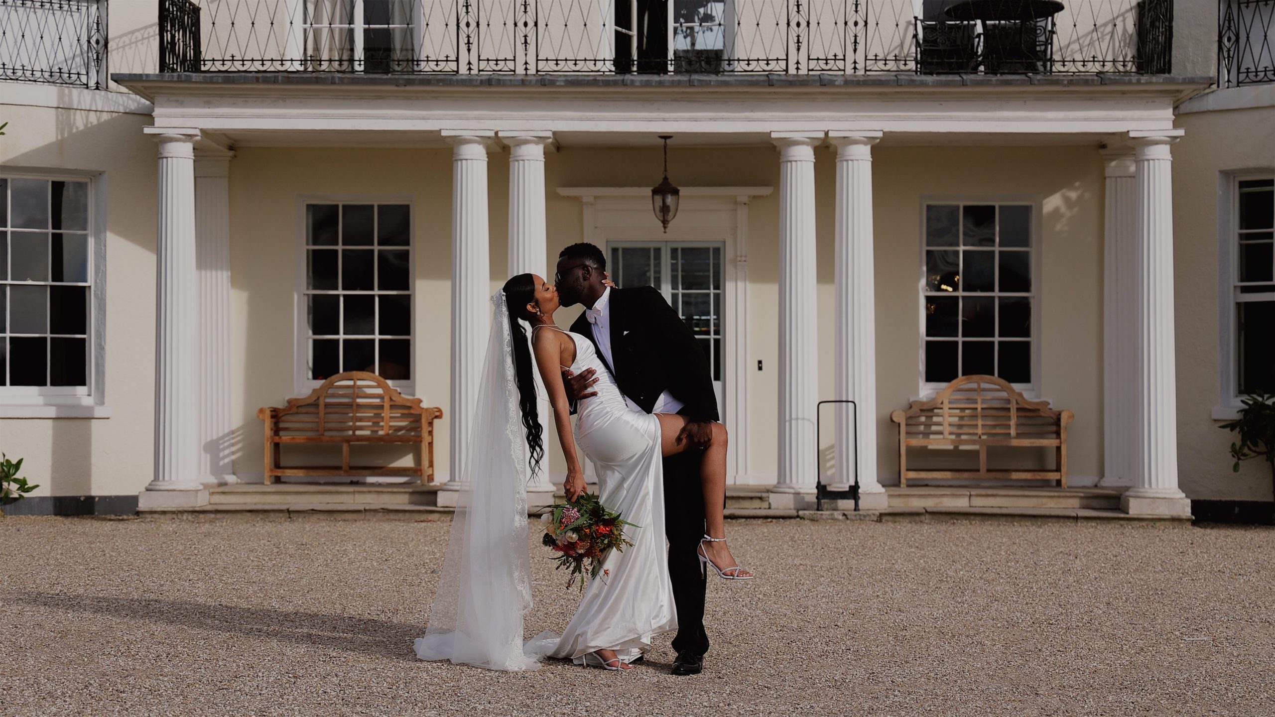 A groom kisses his bride while dipping her in front of Rockbeare Manor