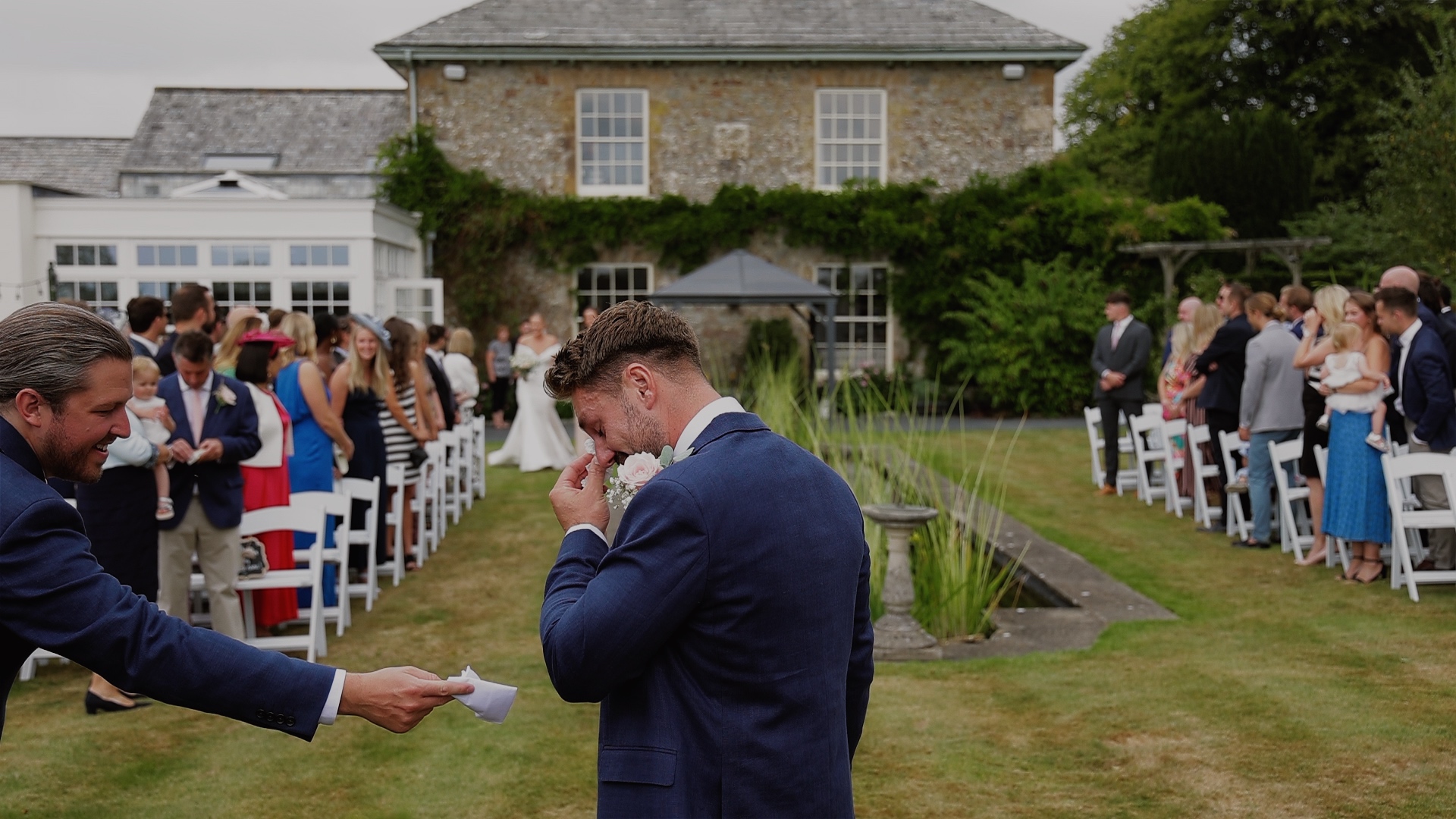 An emotional groom wipes tears away as bride walks down the aisle at Glebe House