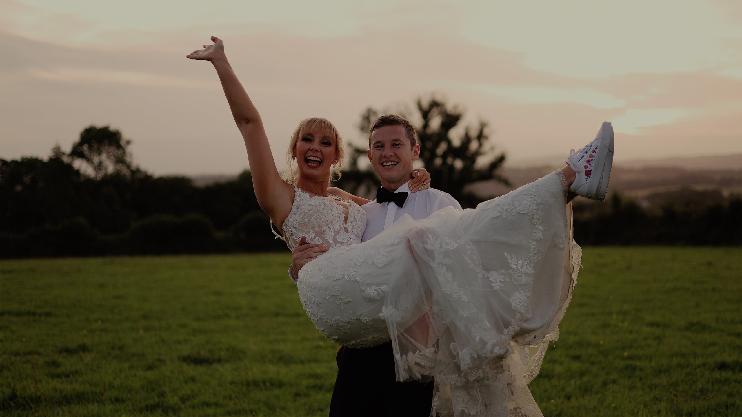 A groom picking up his  happy bride at sunset in a field