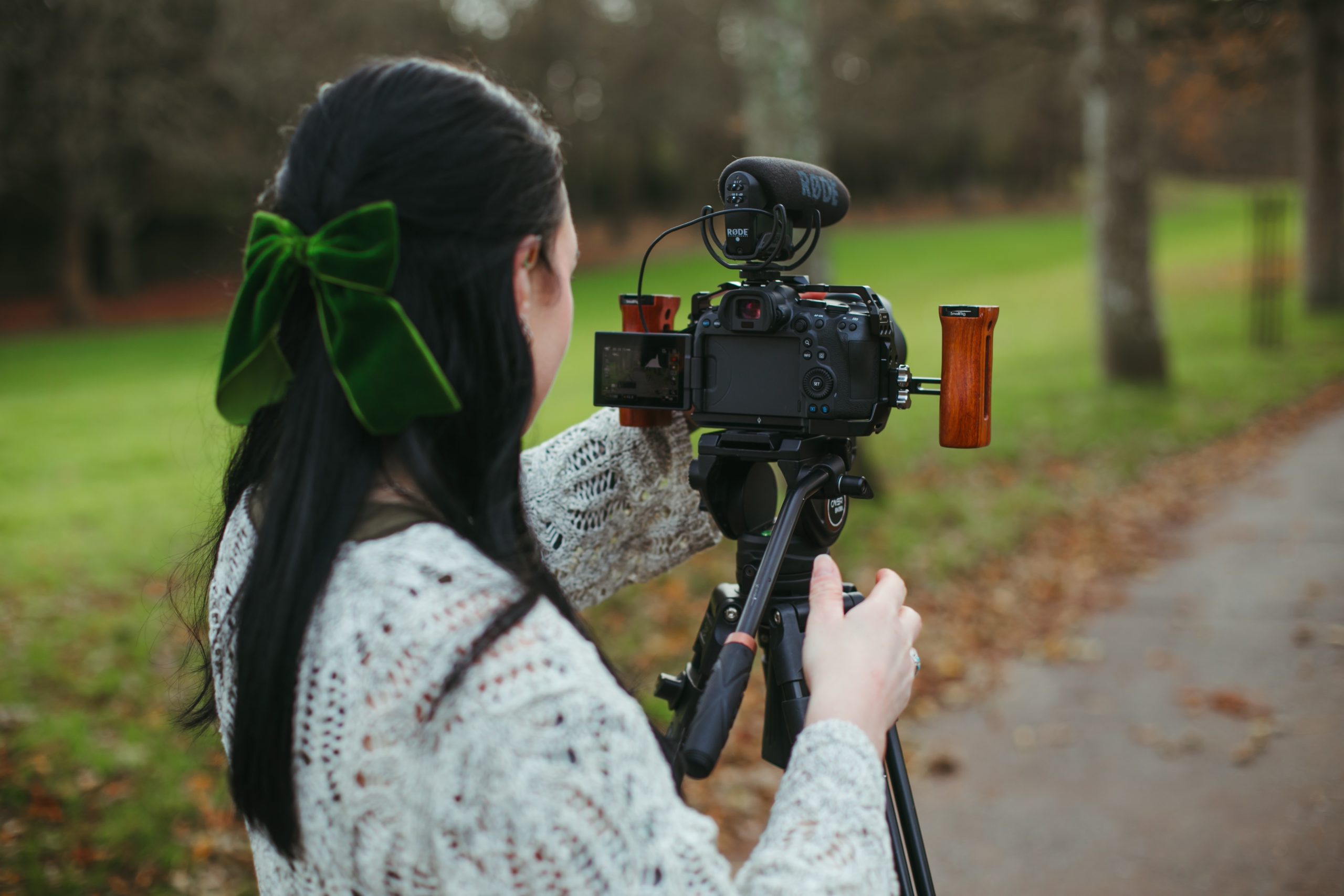 A female wedding videographer standing behind a tripod mounted camera