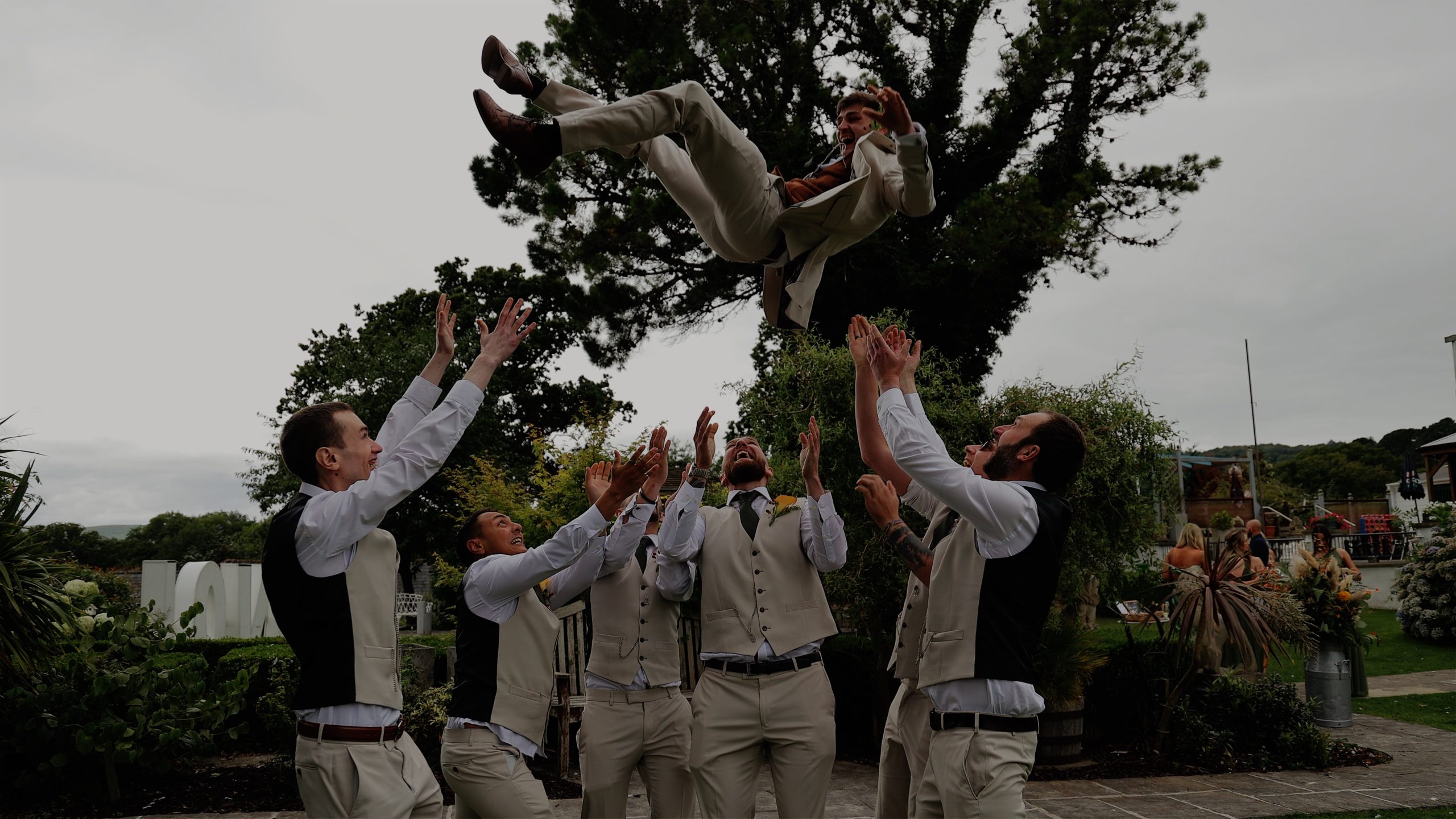 A groom thrown in the air by his groomsmen at a wedding