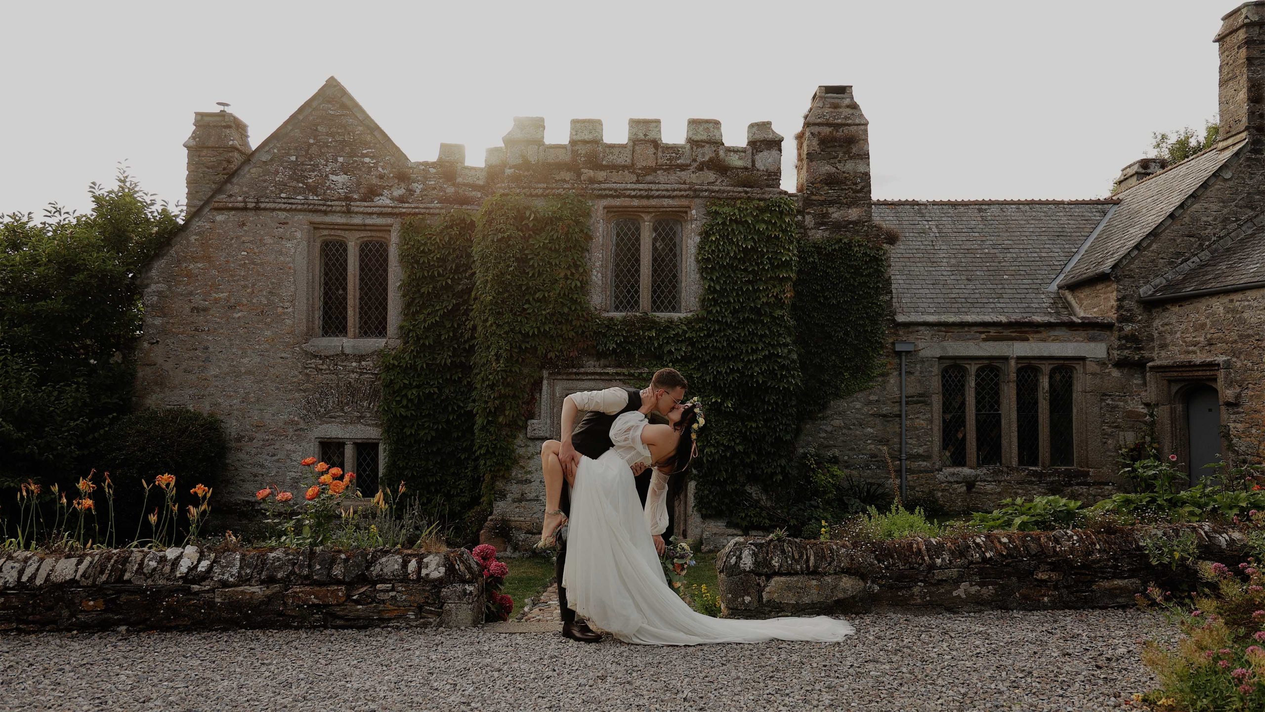 A groom kisses his bride while dipping her in front of Rockbeare Manor
