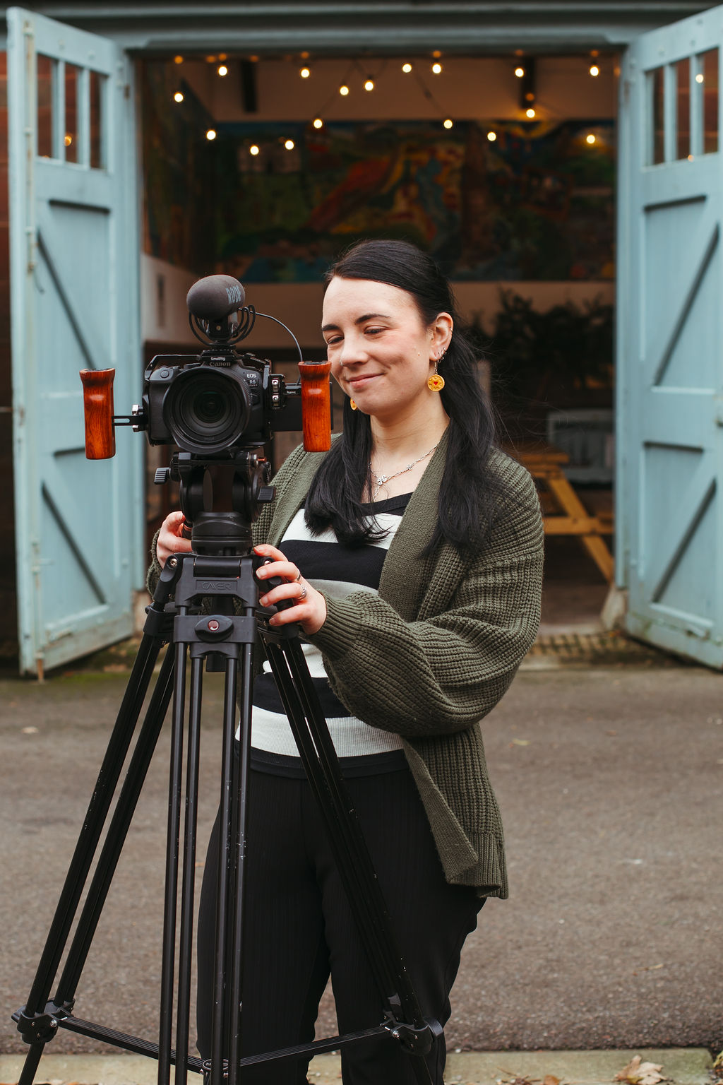 FMP_20 A female wedding videographer smiling at a camera tripod