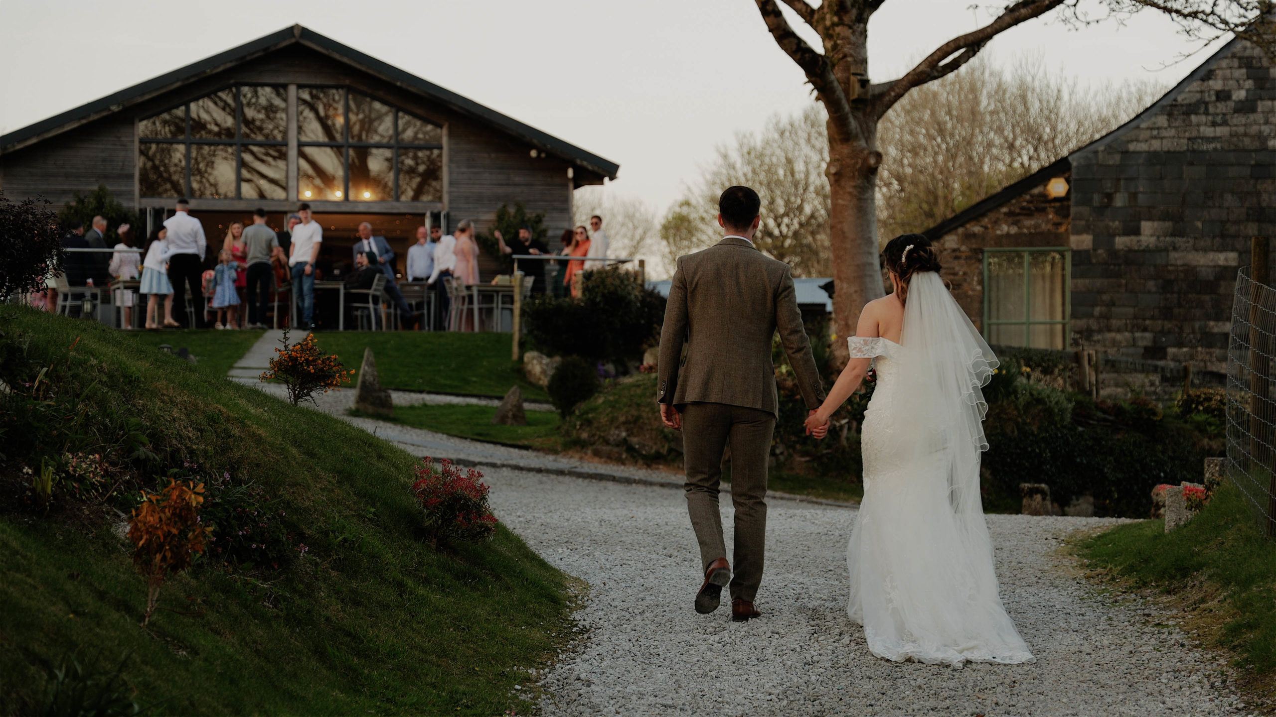 Georgia & Scott The Green walk back to venue A bridesmaid sneaking under the veil while the couple have a kiss at Harefield Barn