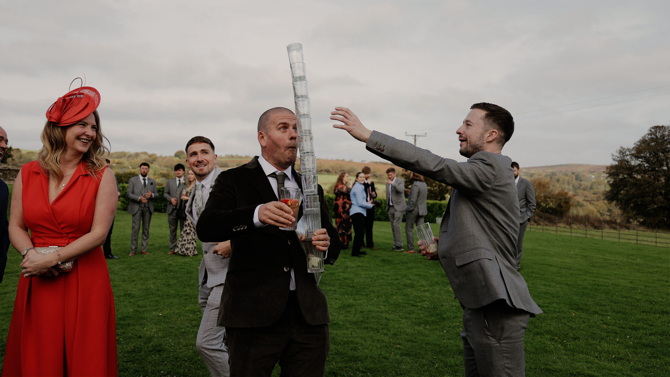 Jack & Emma Trevenna guest glass tower A bride and groom walking along and having fun with their wedding party in the background
