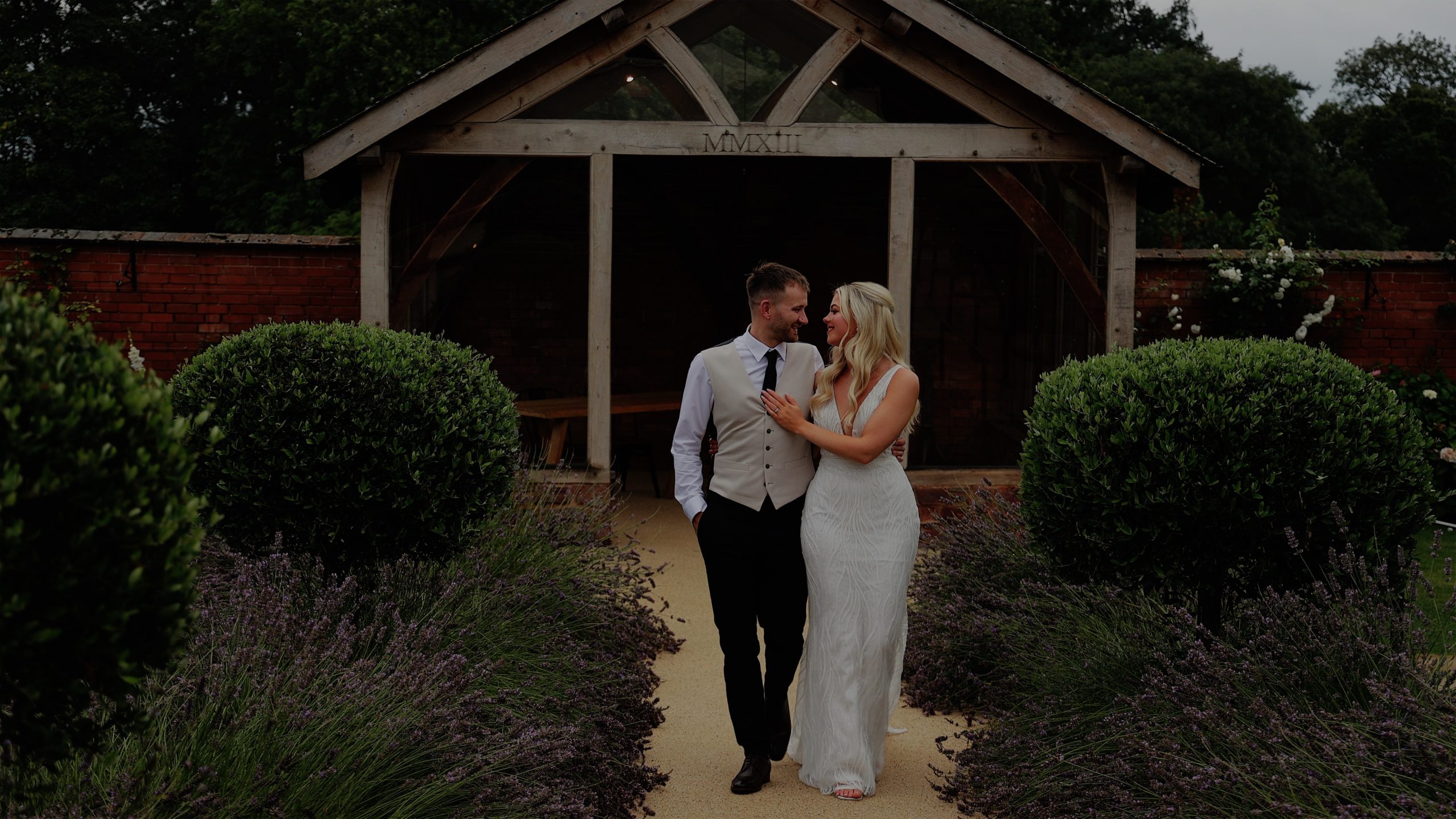 Bride and groom walking arm in arm through garden path at Upton Barn & Walled Garden wedding venue in Devon